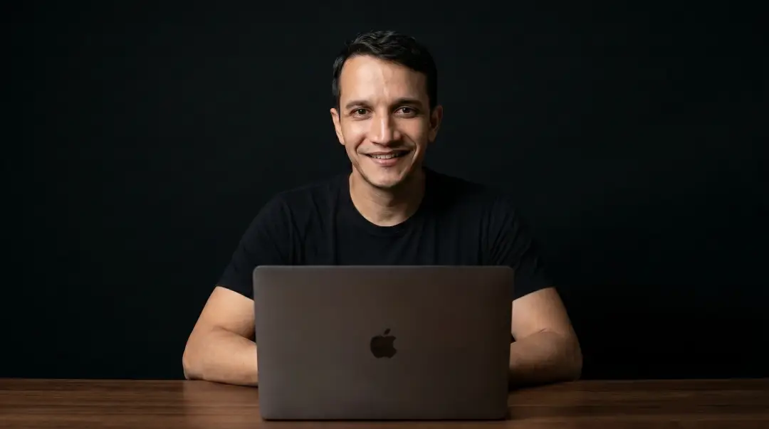 Djean Moraes sentado atrás do notebook, em fundo verde-petróleo